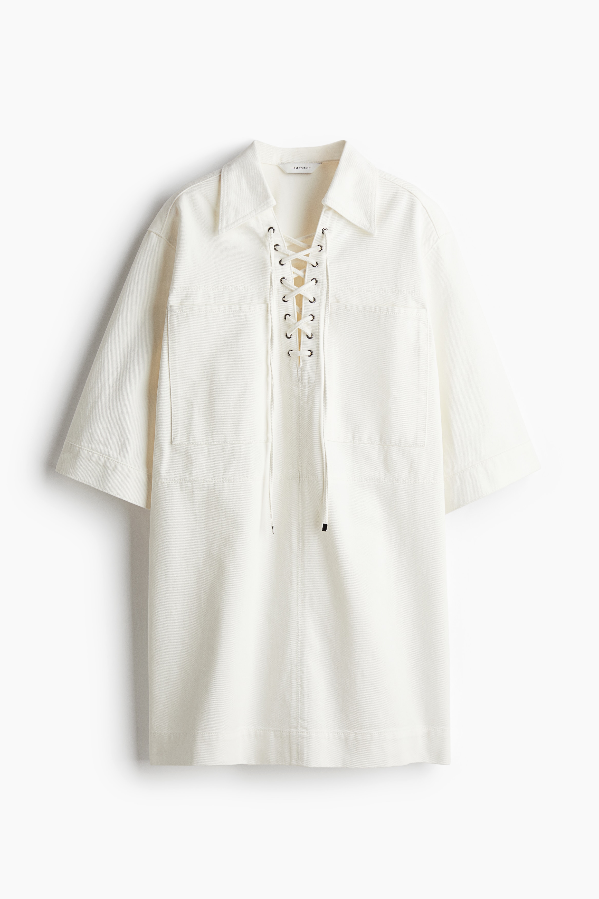 코튼 데님 소재의 루즈핏 미니 원피스. 앞면에 레이스업 디테일이 있는 오픈 스타일 칼라. 세미 드롭 숄더. 5부 소매. 큼직한 가슴 패치포켓. 이미지