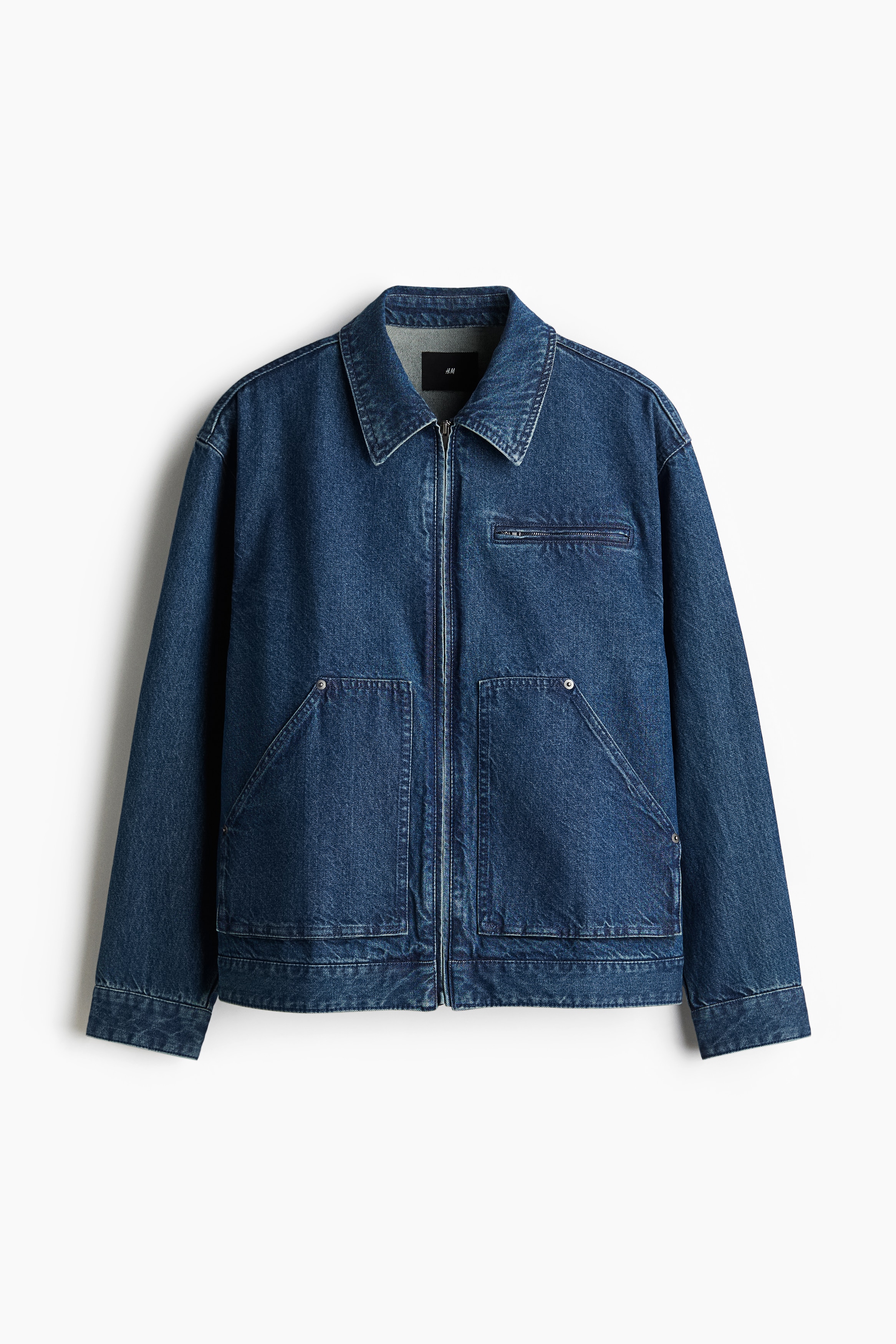 탄탄한 코튼 데님 소재의 긴소매 재킷. 칼라와 앞면 지퍼가 있음. 뒷면 요크. 트임과 버튼이 있는 소맷단. 가슴 지퍼 포켓. 앞면 패치포켓. 넉넉하지만 오버사이즈보다는 약간 피트되는 루즈핏 실루엣. 안감 생략. 이미지