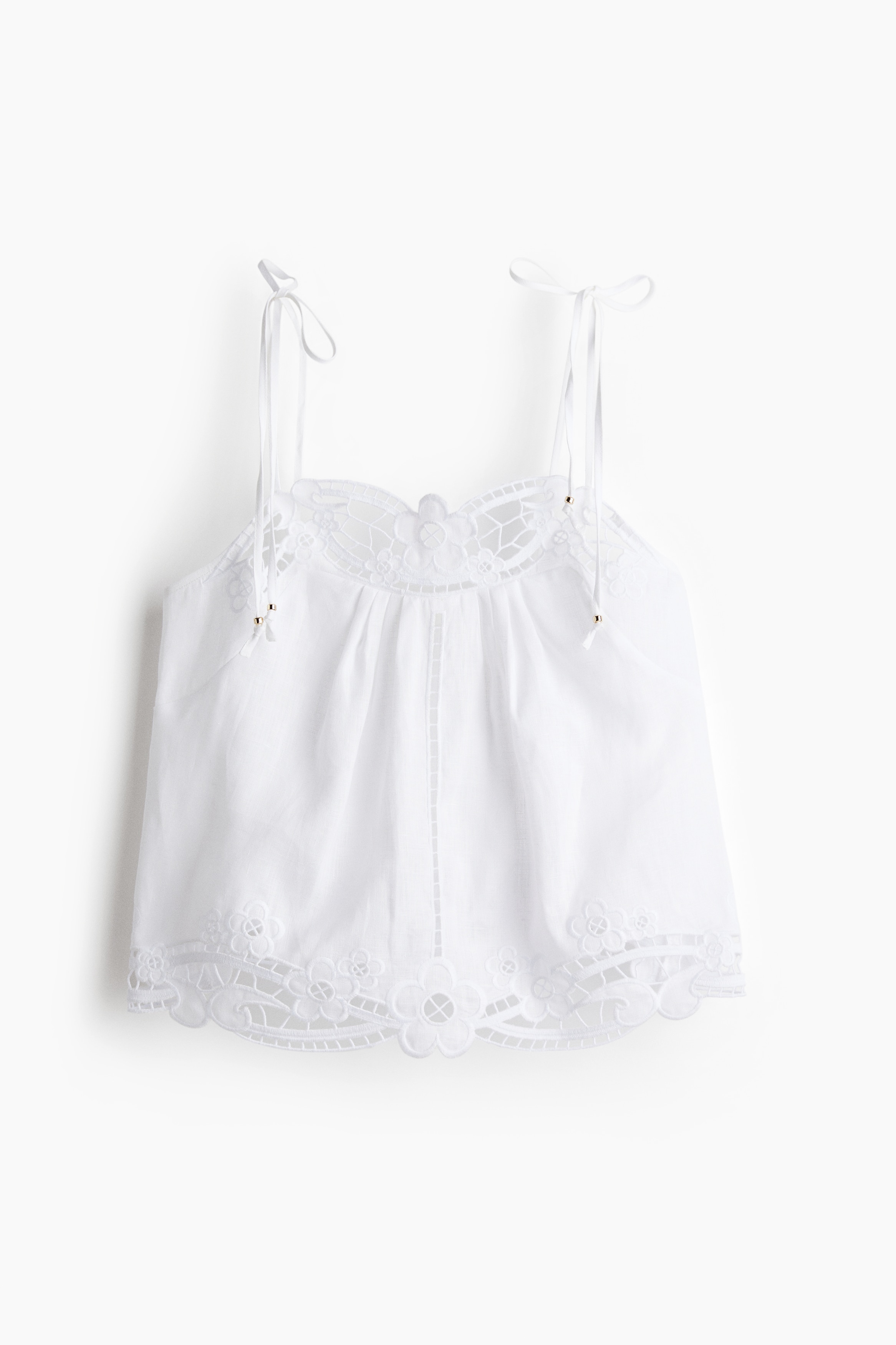 펀칭 자수 장식이 있는 가벼운 리넨 소재의 탑. 스위트하트 넥. 금속 비즈 장식이 있으며 상단을 묶는 가느다란 어깨 스트랩. 섬세한 앞면 플리츠 장식. 뒷면 상단에 밴딩이 내장된 세미 플레어 라인. 이미지