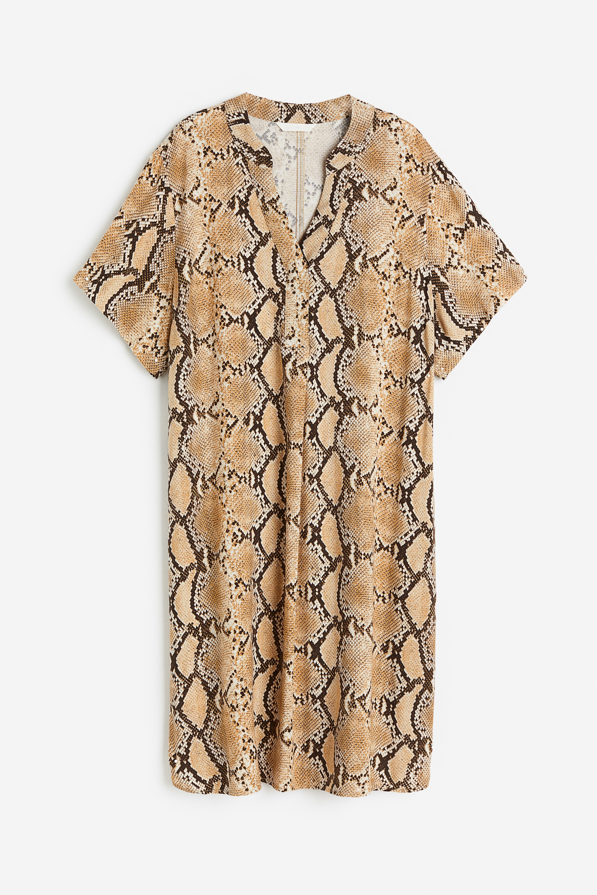 비스코스 소재의 V넥 반소매 튜닉. 짧은 스탠드 칼라. 드롭 숄더. 옆면 하단에 트임이 있으며, 뒷면이 조금 더 긴 라운드 헴라인. 안감 생략. 이미지