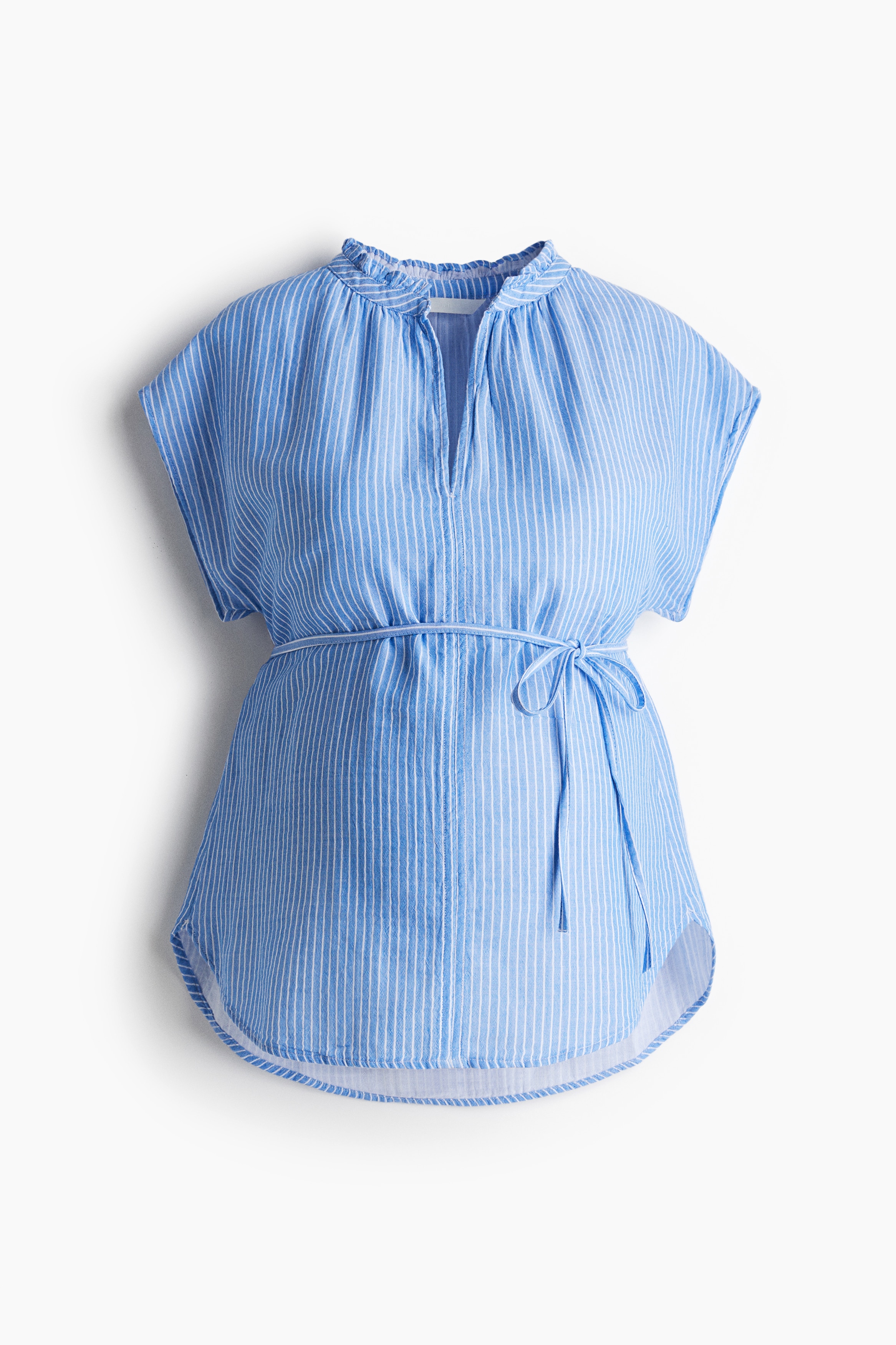 부드러운 코튼 모슬린 소재의 블라우스. 프릴로 마감된 밴드 칼라 둘레에 주름이 잡혀 있음. 앞면 상단 V자 트임. 캡소매. 가슴 아래에 가느다란 탈부착식 끈 벨트를 두른 디자인. 라운드 헴라인. 이미지