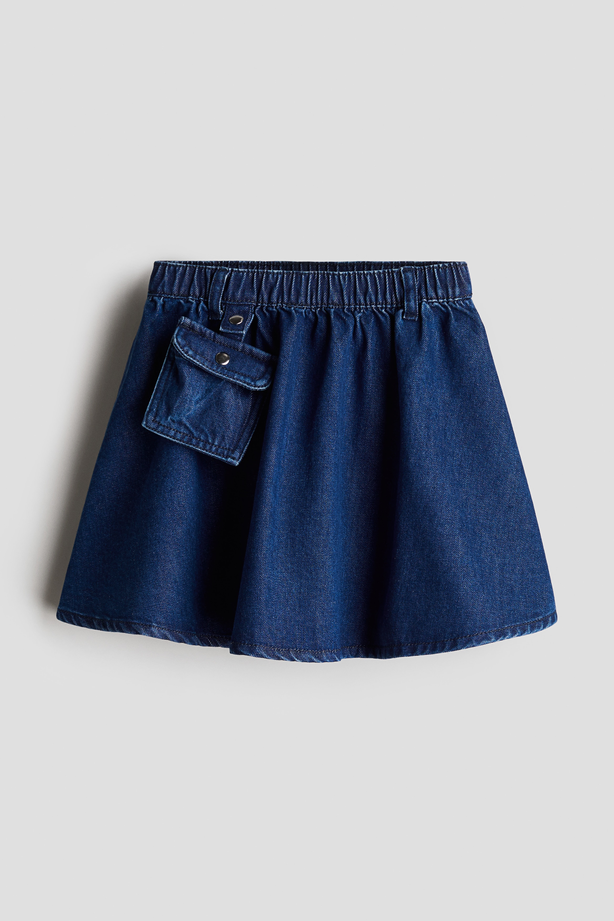 부드러운 코튼 데님 소재의 플레어 스커트. 스냅버튼이 있는 탈부착식 플랩포켓. 신축성 허릿단. 이미지
