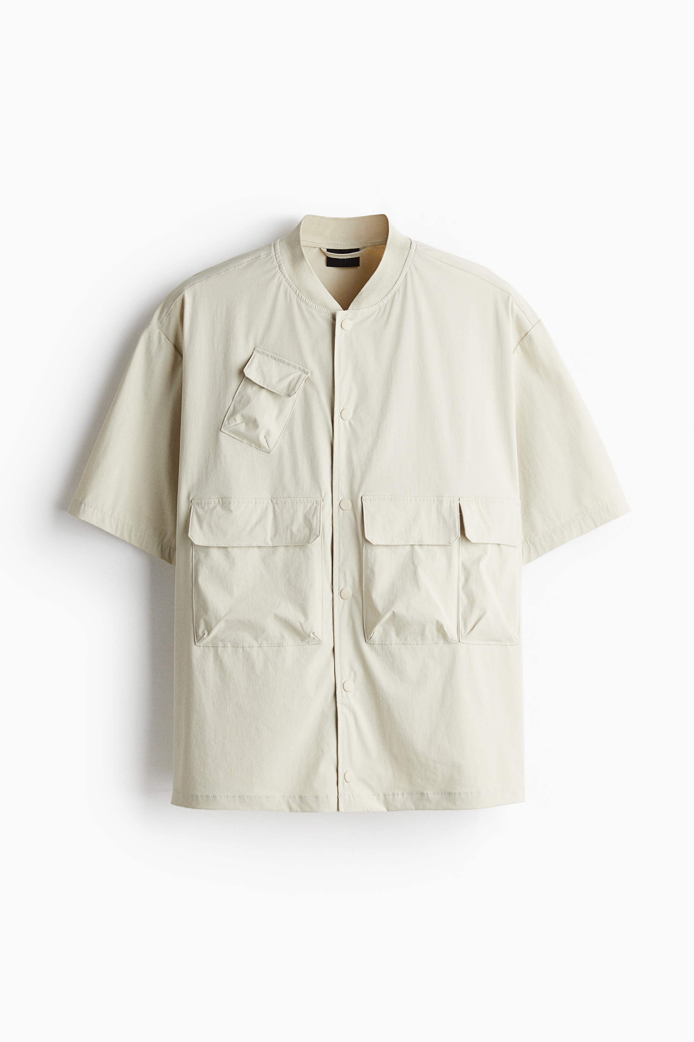 우븐 소재의 반소매 유틸리티 재킷. 리브드 마감된 스탠드 칼라. 스냅버튼 클로저. 스트레잉트 헴라인. 다양한 크기로 마감된 앞면 플랩포켓. 넉넉하지만 오버사이즈보다는 약간 피트되는 루즈핏 실루엣. 이미지