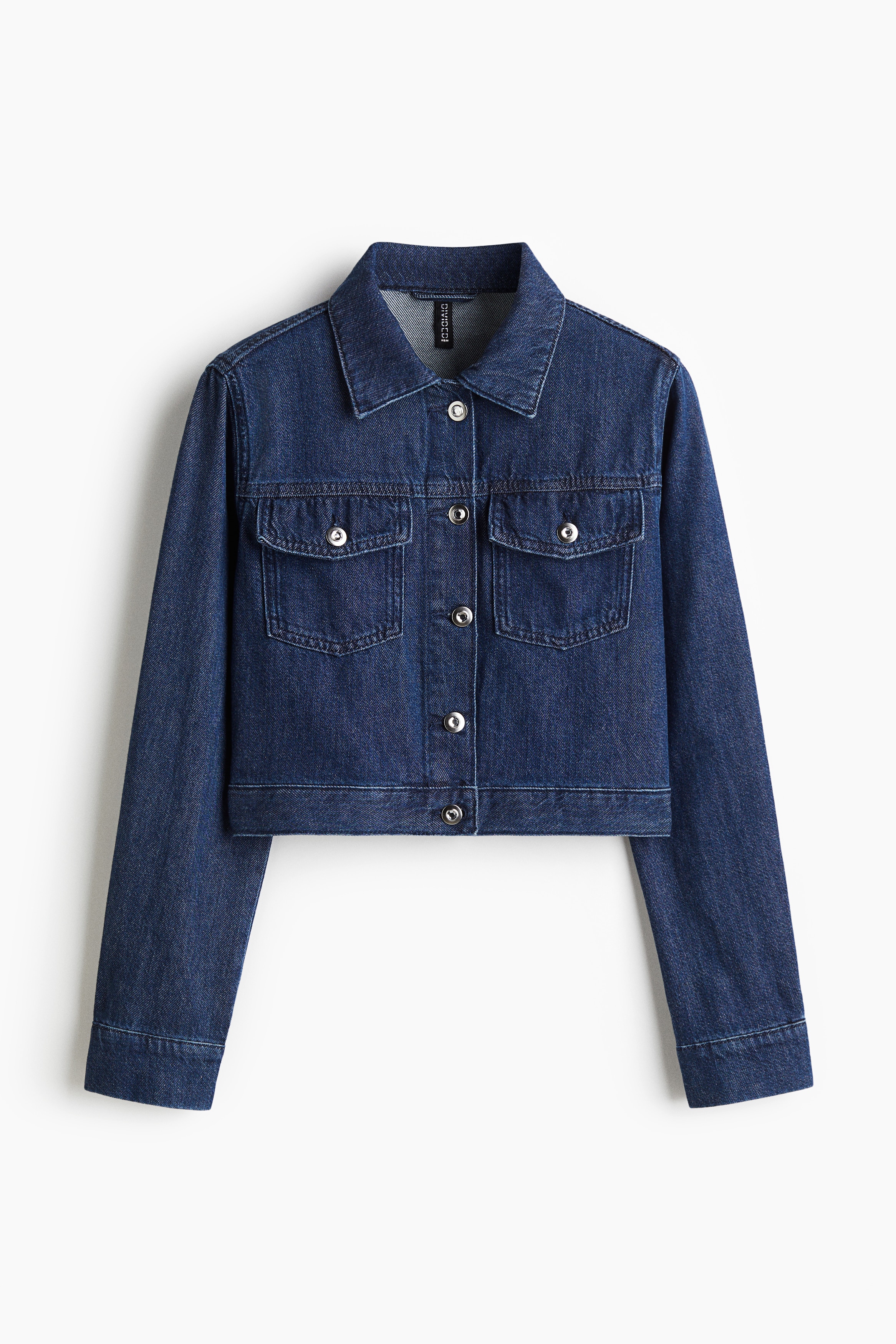 칼라가 있는 탄탄한 코튼 데님 소재의 크롭트 재킷. 앞면과 가슴 플래포켓에 버튼이 있음. 플래킷과 링크 버튼이 있는 긴소매. 소맷단 버튼. 이미지