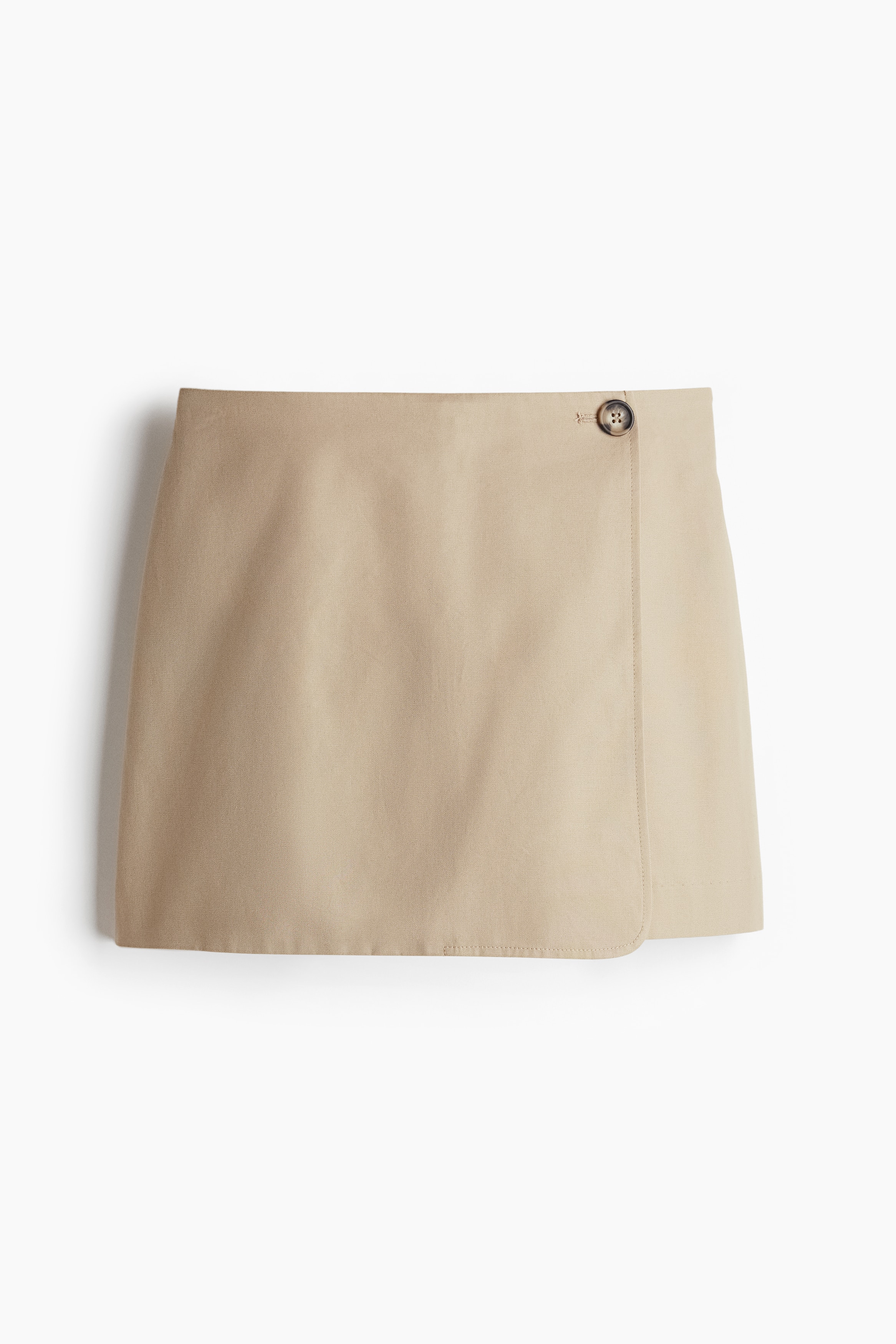 코튼 트윌 소재의 하이웨이스트 스코트. 한쪽 옆면에 버튼이 있는 랩스타일. 앞면 히든 지퍼. 뒷면 페이크 웰트포켓. 이미지