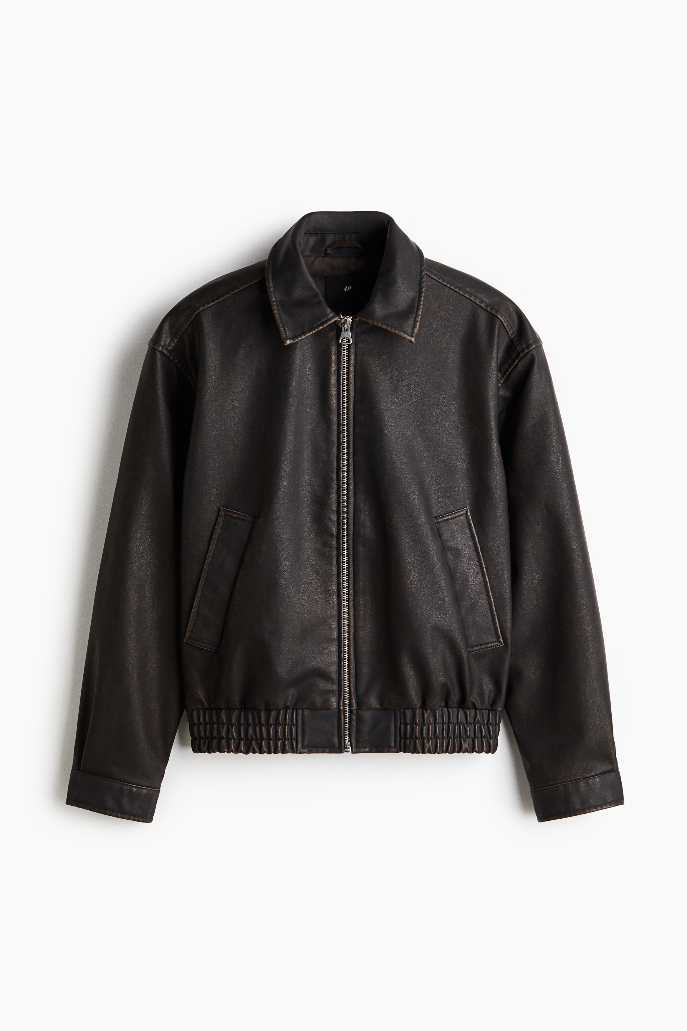 워싱처리된 듯한 코팅 패브릭 소재의 재킷. 칼라와 앞면 지퍼가 있음. 사선 방향의 옆면 포켓. 스냅버튼으로 여닫는 내부 포켓. 긴소매. 소맷단 스냅버튼. 스모킹 주름으로 마감된 신축성 아랫단. 넉넉하지만 오버사이즈보다는 약간 피트되는 루즈핏 실루엣. 안감 부착. 이미지