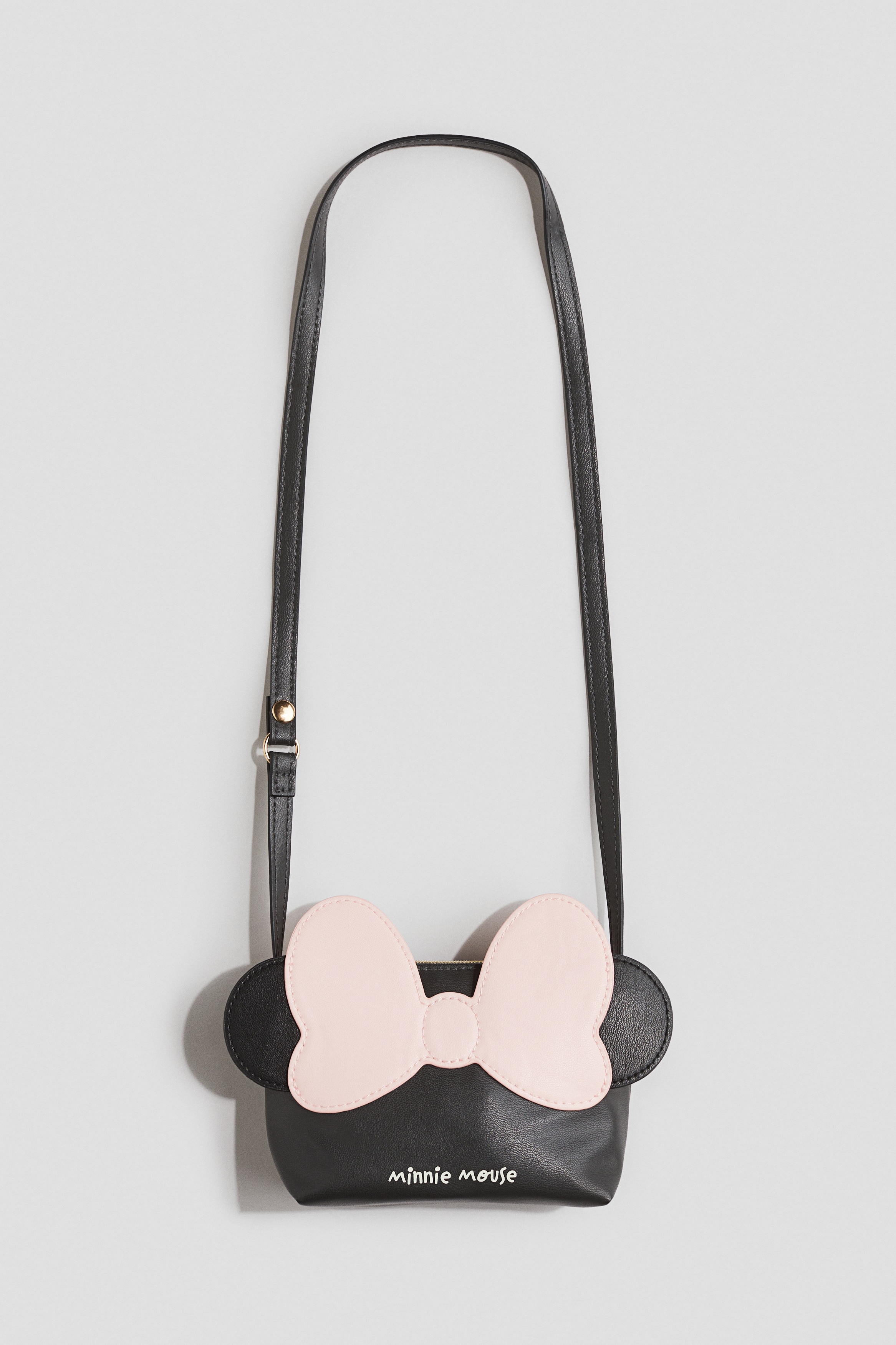 코팅된 패브릭 소재의 숄더백. 아플리케 장식. 상단 지퍼. 가느다란 어깨 스트랩 한쪽 끝에 분리되는 스냅버튼이 있음. 이미지