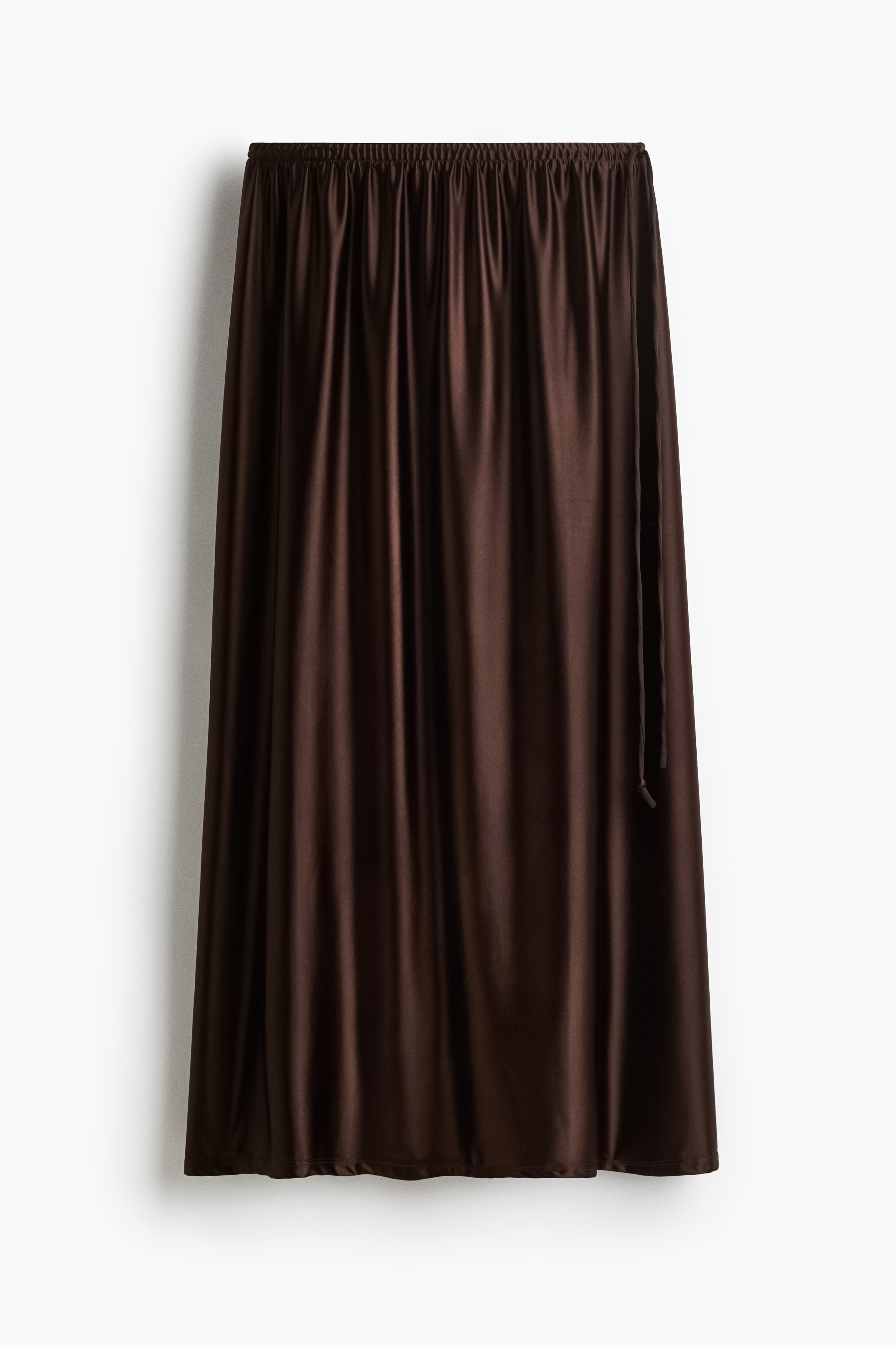 윤기가 흐르는 광택성 스트레치 소재의 미디 스커트. 하이웨이스트. 밴딩이 내장된 허릿단의 가는 드로스트링을 옆면에서 매듭짓는 디자인. 안감 생략. 이미지