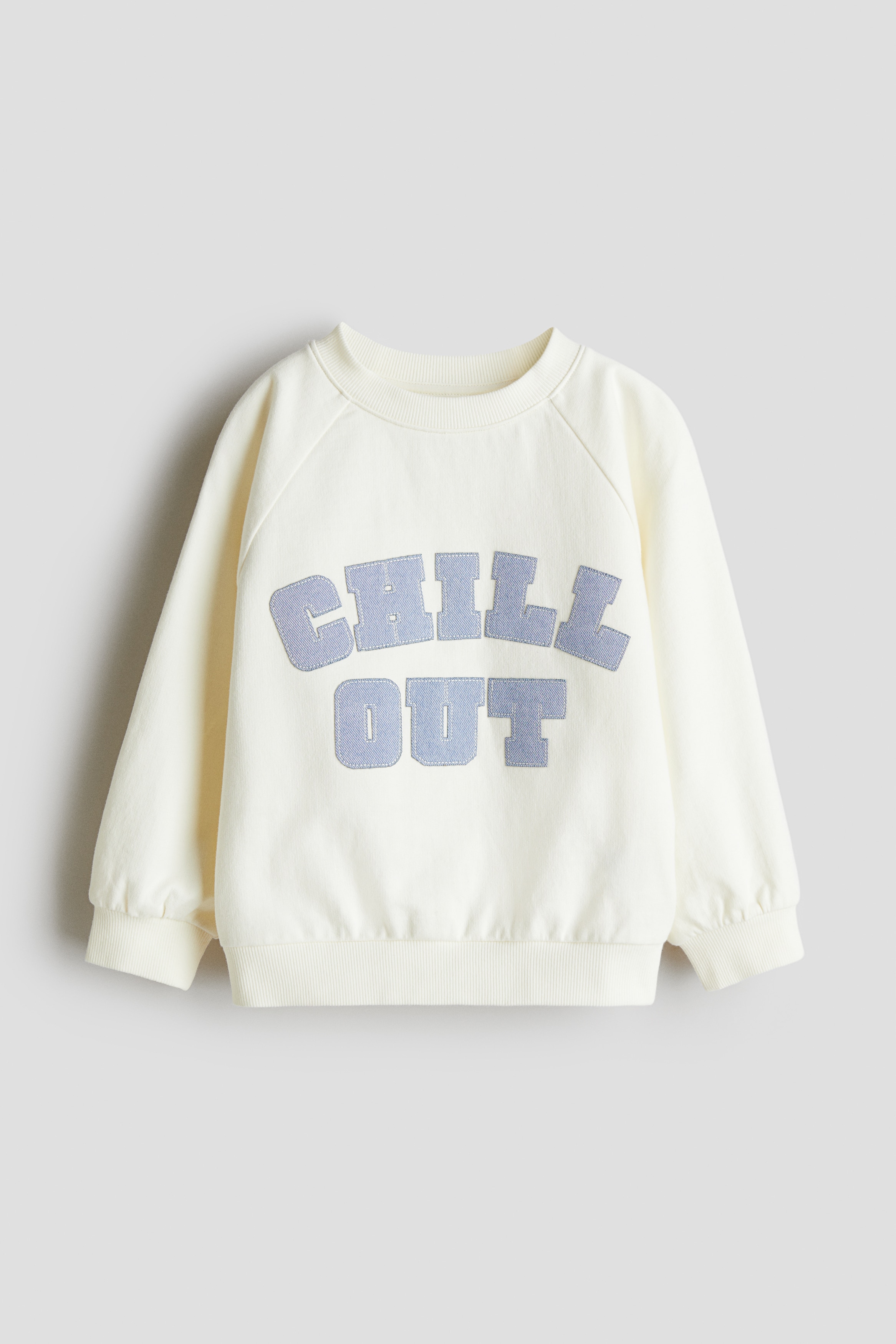 앞면에 아플리케가 있는 가벼운 코튼 소재의 스웨트셔츠. 라운드넥. 래글런 스타일의 긴소매. 리브드 트리밍. 이미지