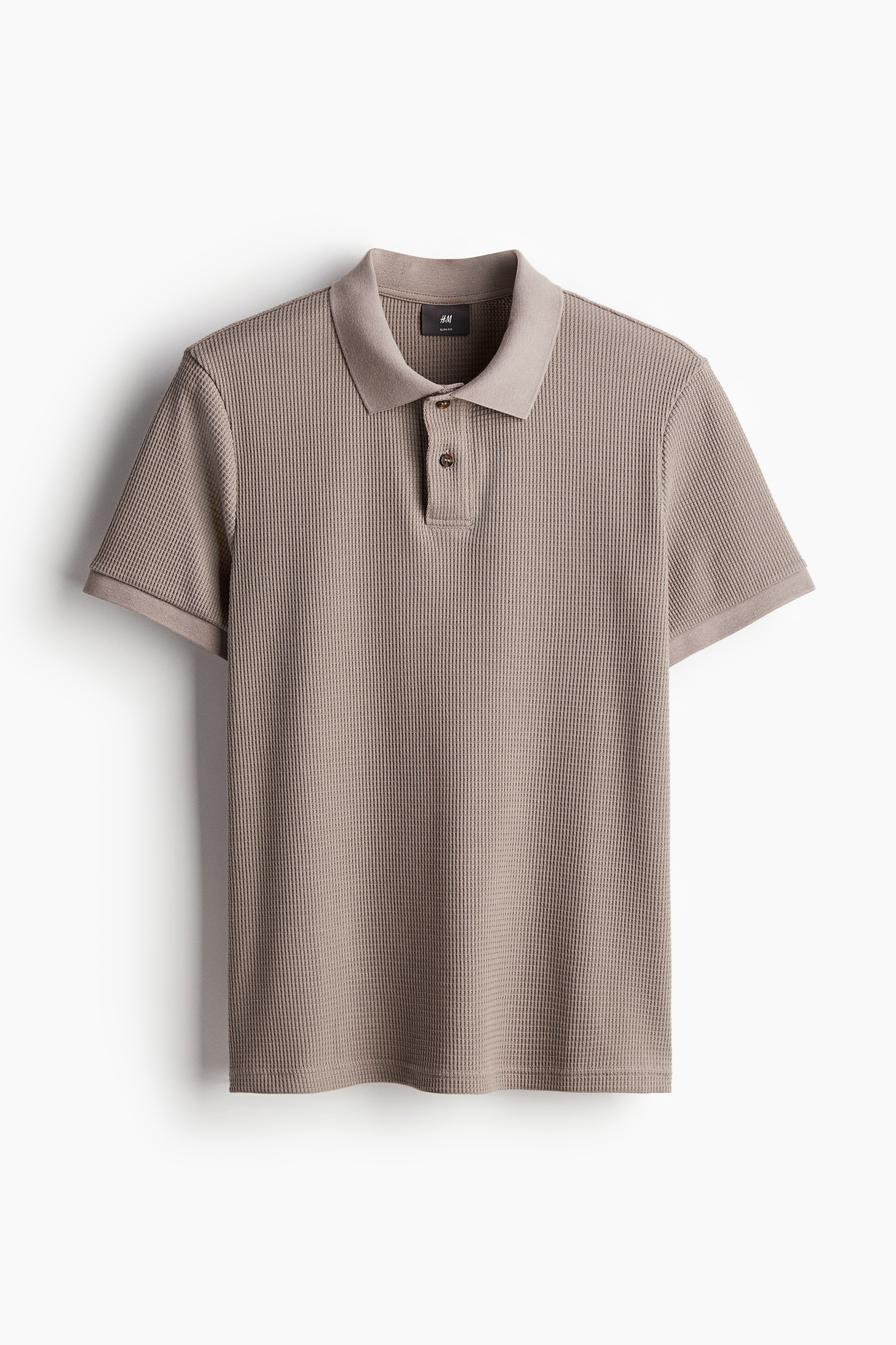 와플 텍스처가 있는 코튼 혼방 저지 소재의 슬림핏 폴로셔츠. 리브드 칼라. 상단 버튼. 반소매. 양쪽 옆면 하단에 짧은 트임이 있는 스트레이트 헴라인. 이미지