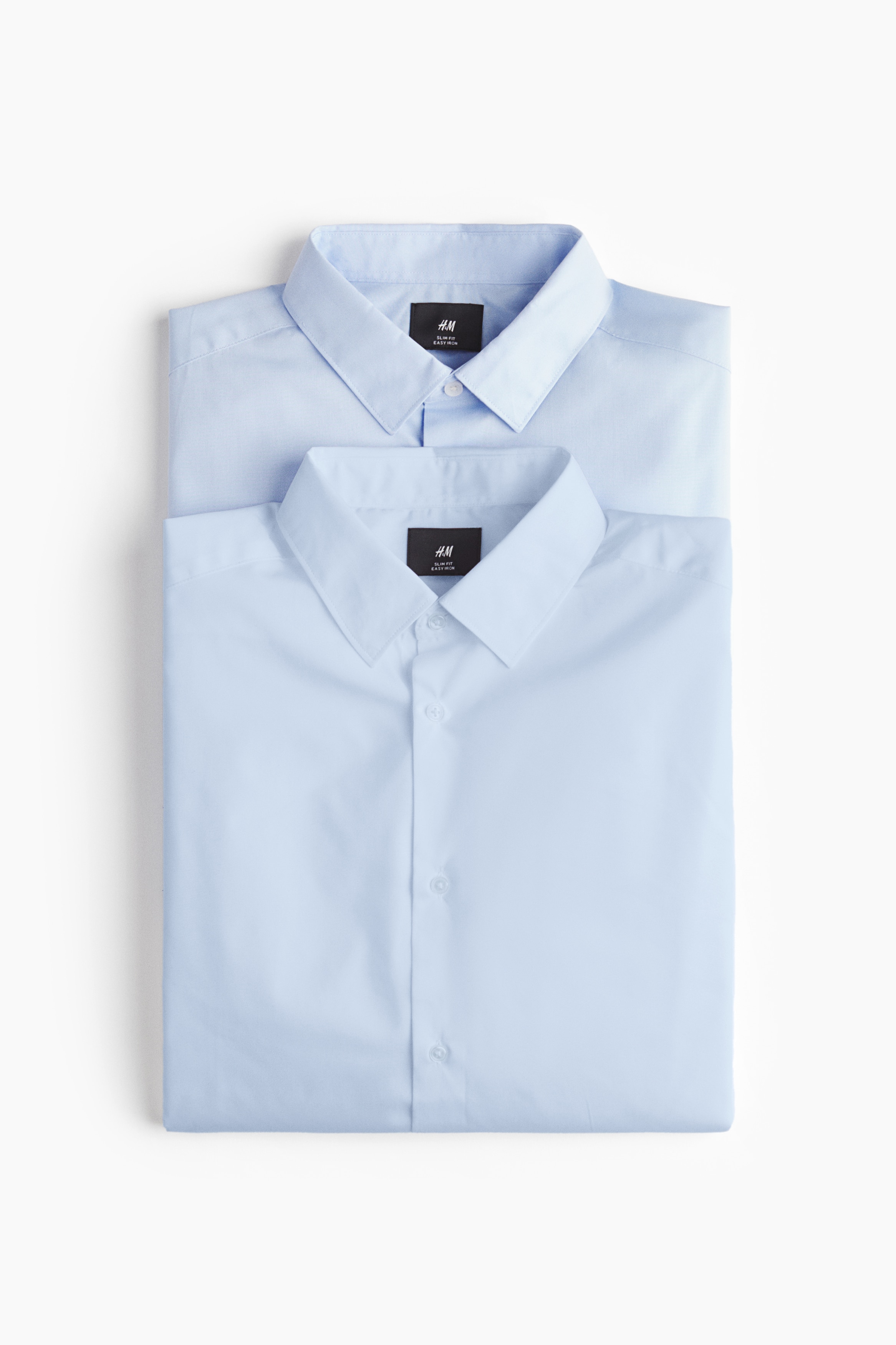 다림질이 용이한 소재의 셔츠. 턴다운 칼라. 버튼단이 있는 프렌치 프런트 스타일. 뒷면 요크. 플래킷과 링크 버튼이 있는 긴소매. 버튼이 있는 소맷단. 세미 라운드 헴라인. 바디 라인을 감싸며 피트되는 슬림핏 실루엣. 이미지