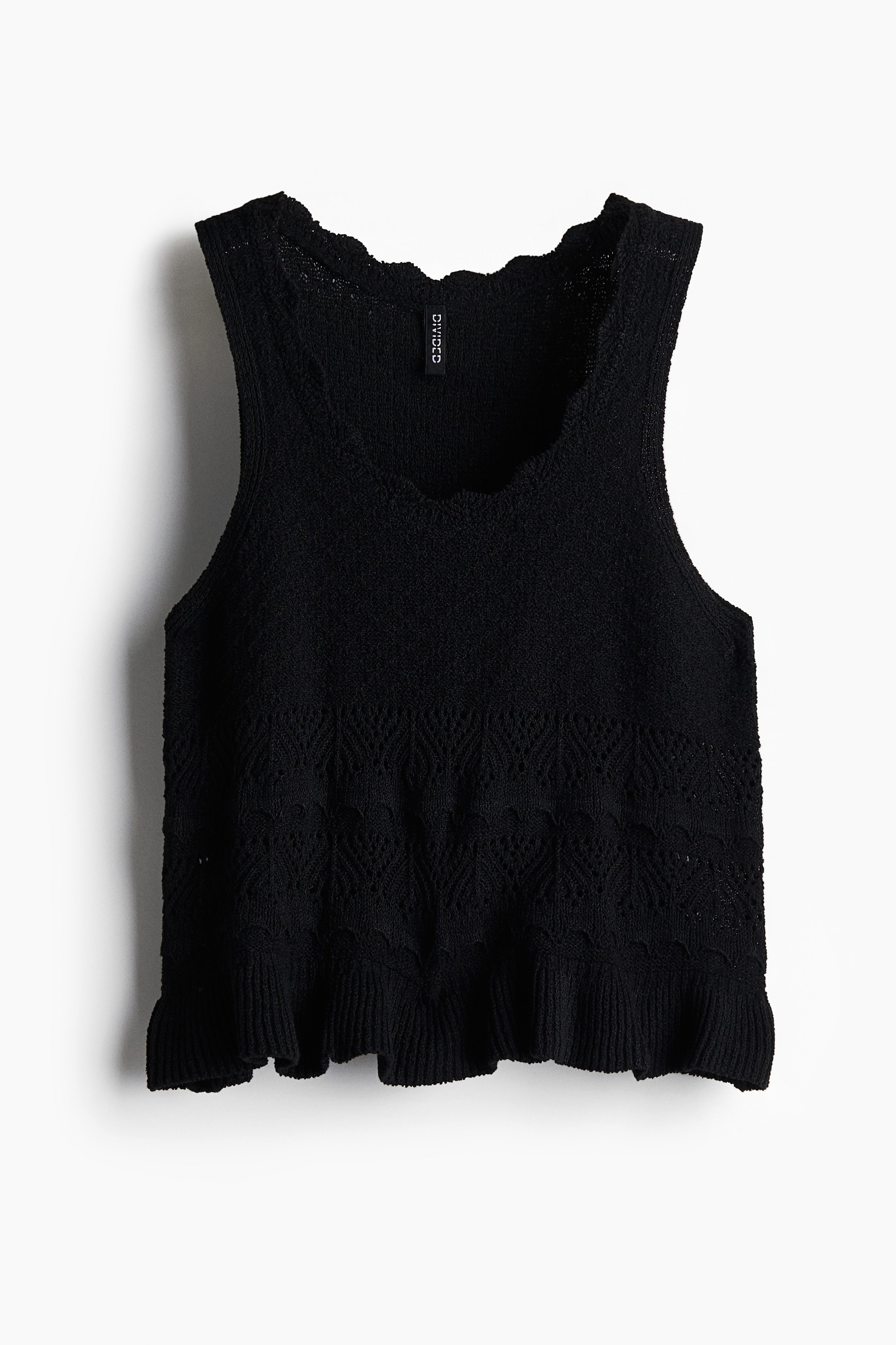 부드러운 크로셰 느낌의 짧은 슬리브리스 니트 탑. 스캘럽트 라인으로 트리밍된 깊게 파인 라운드넥. 리브드 프릴 마감의 아랫단. 이미지