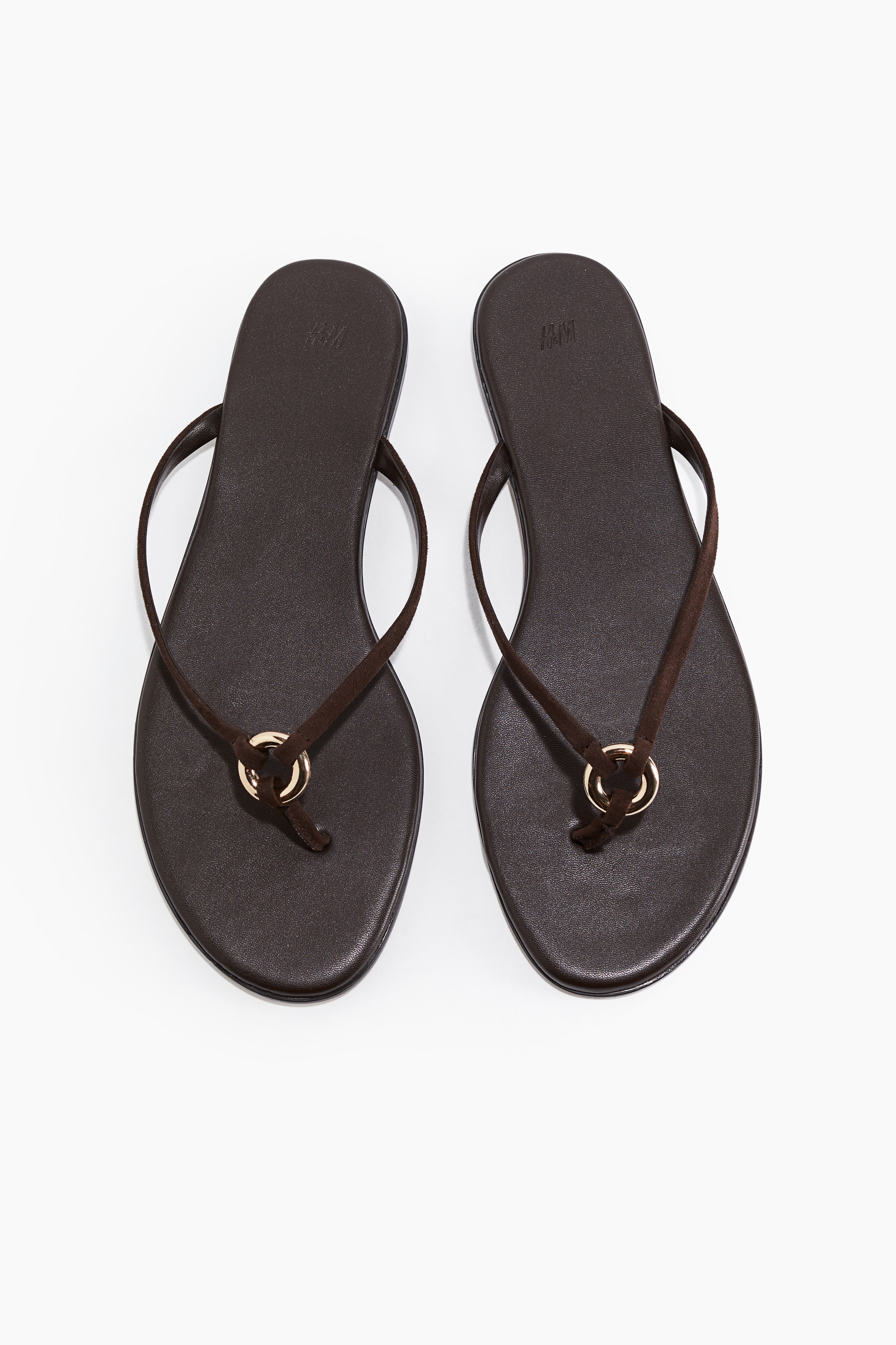 라운드 토 스타일의 플립플랍 샌들. 가는 발등 스트랩이 앞부분의 청키한 금속 링에 연결된 디자인. 이미지