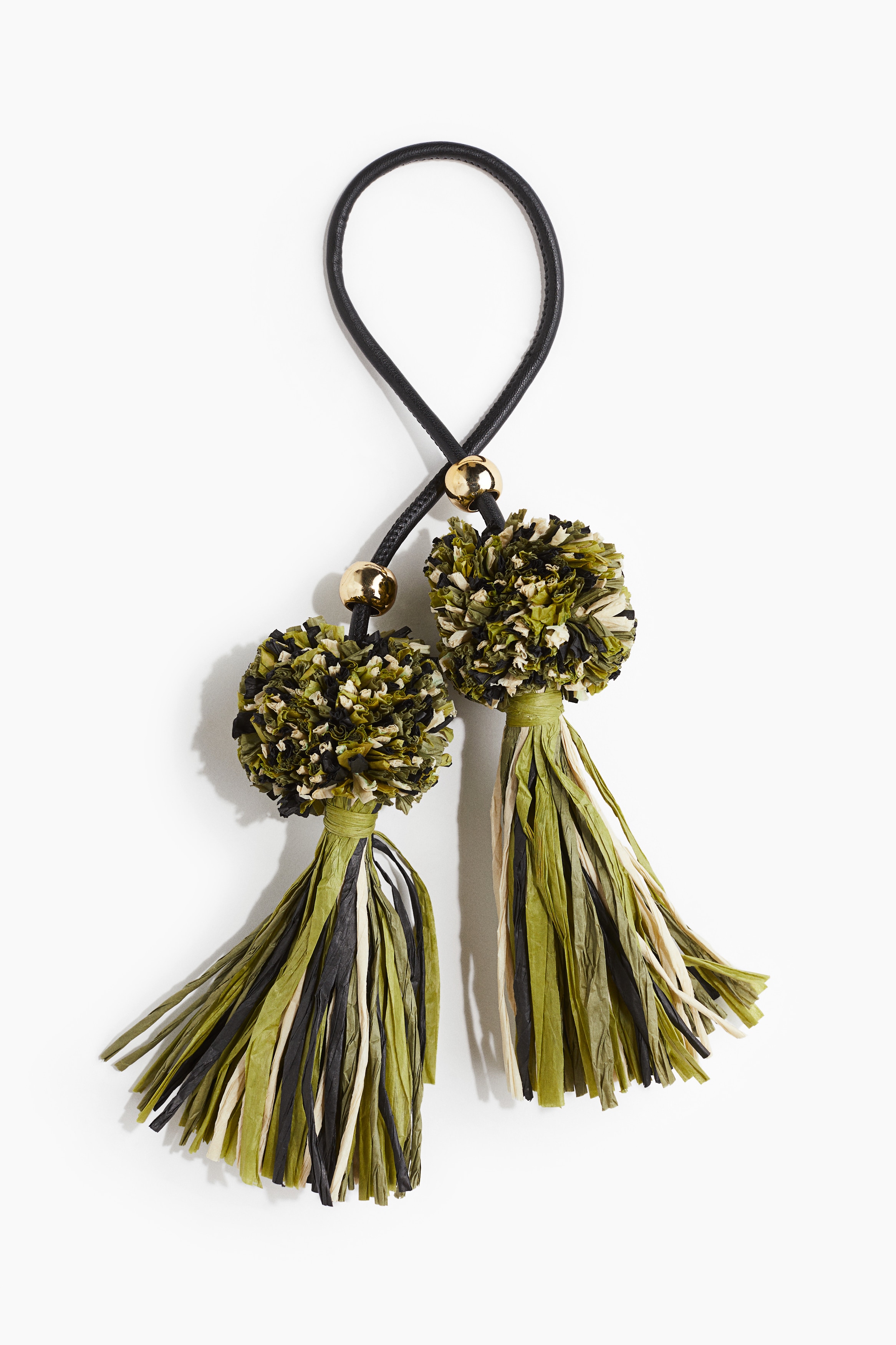 가는 튜브 모양의 코팅처리된 패브릭 스트랩을 사용한 가방 챰 장식. 골드 컬러의 비즈 디테일. 끝부분이 페이퍼 스트로 소재의 볼드한 폼폼과 태슬로 마감됨. 이미지