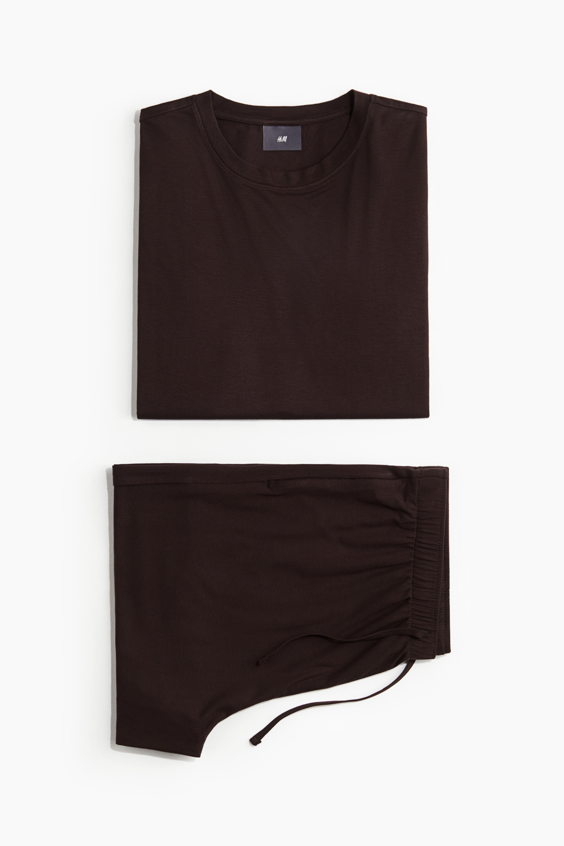 스트레치 비스코스 저지 소재의 파자마 상하 세트. 상의 - 리브드 라운드넥 스타일의 티셔츠. 스트레이트 헴라인. 하의 - 드로스트링이 있는 신축성 허릿단의 반바지. 옆면 포켓. 이미지