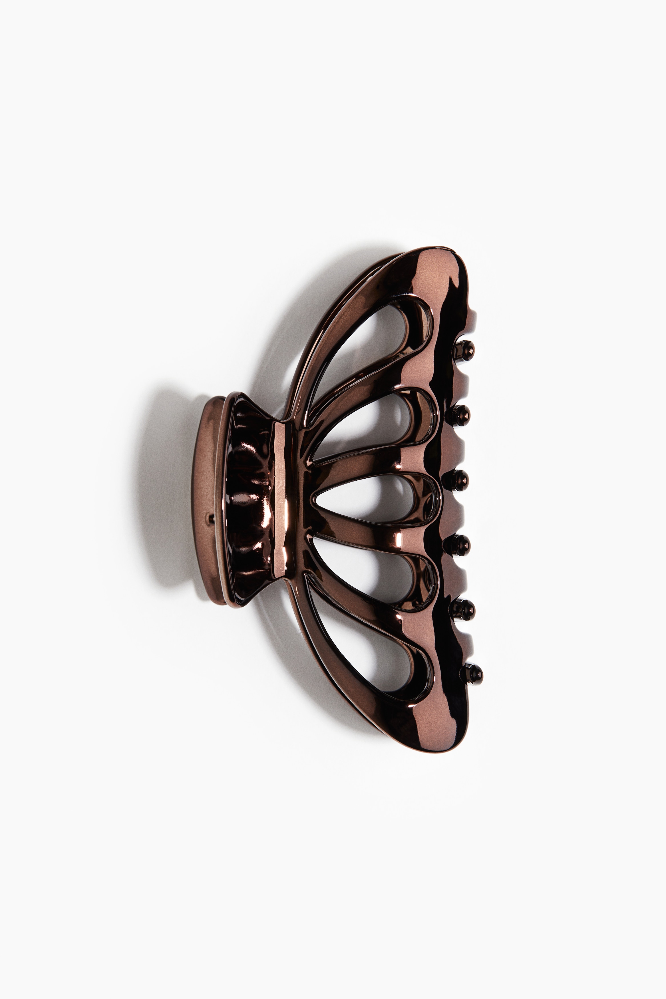 양쪽 옆면에 물방울 모양의 컷아웃 디테일이 있는 플라스틱 헤어 클로. 높이 4.5cm. 폭 9cm. 이미지