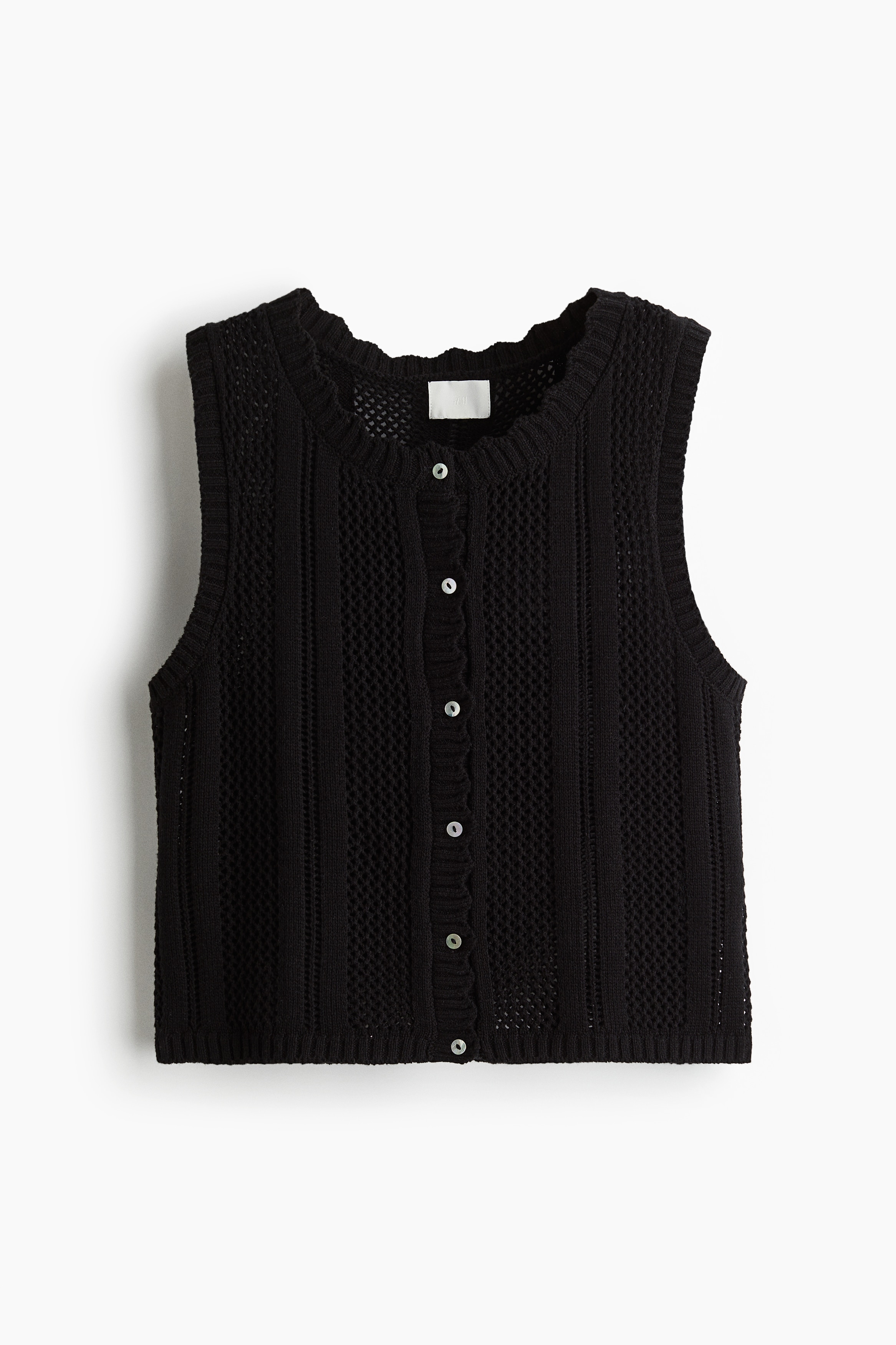 부드러운 홀 니트 소재의 짧은 베스트. 스캘럽트 라인으로 마감된 라운드넥. 앞면 펄 버튼 클로징. 이미지