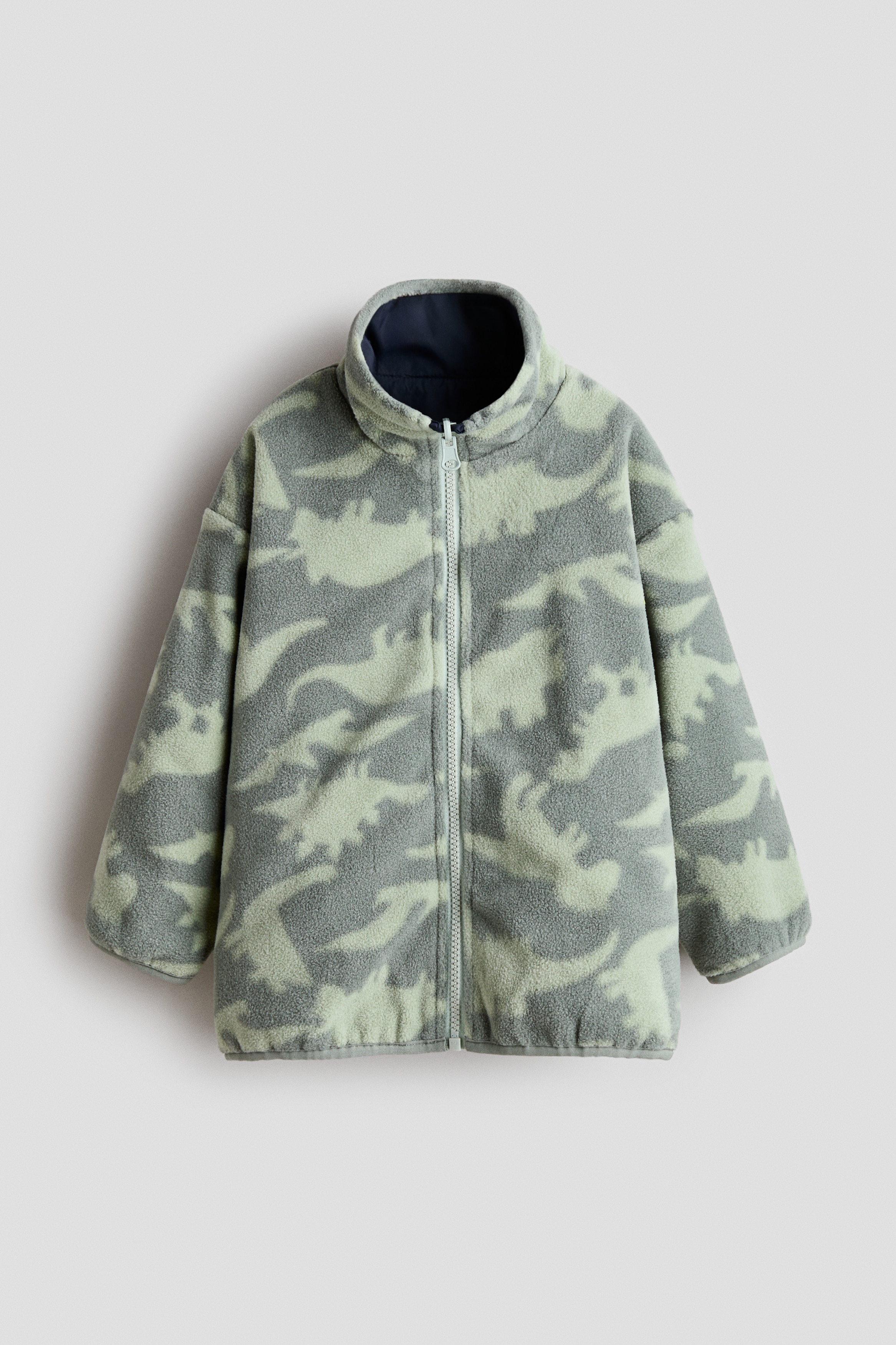 한쪽 면은 프린트가 있는 부드러운 플리스, 반대 면은 단색 나일론 소재로 마감된 양면 재킷. 하이넥. 턱 부분에 쓸림 방지 덮개가 있는 지퍼 클로저. 옆면 포켓. 바인딩처리된 소맷단과 아랫단. 이미지