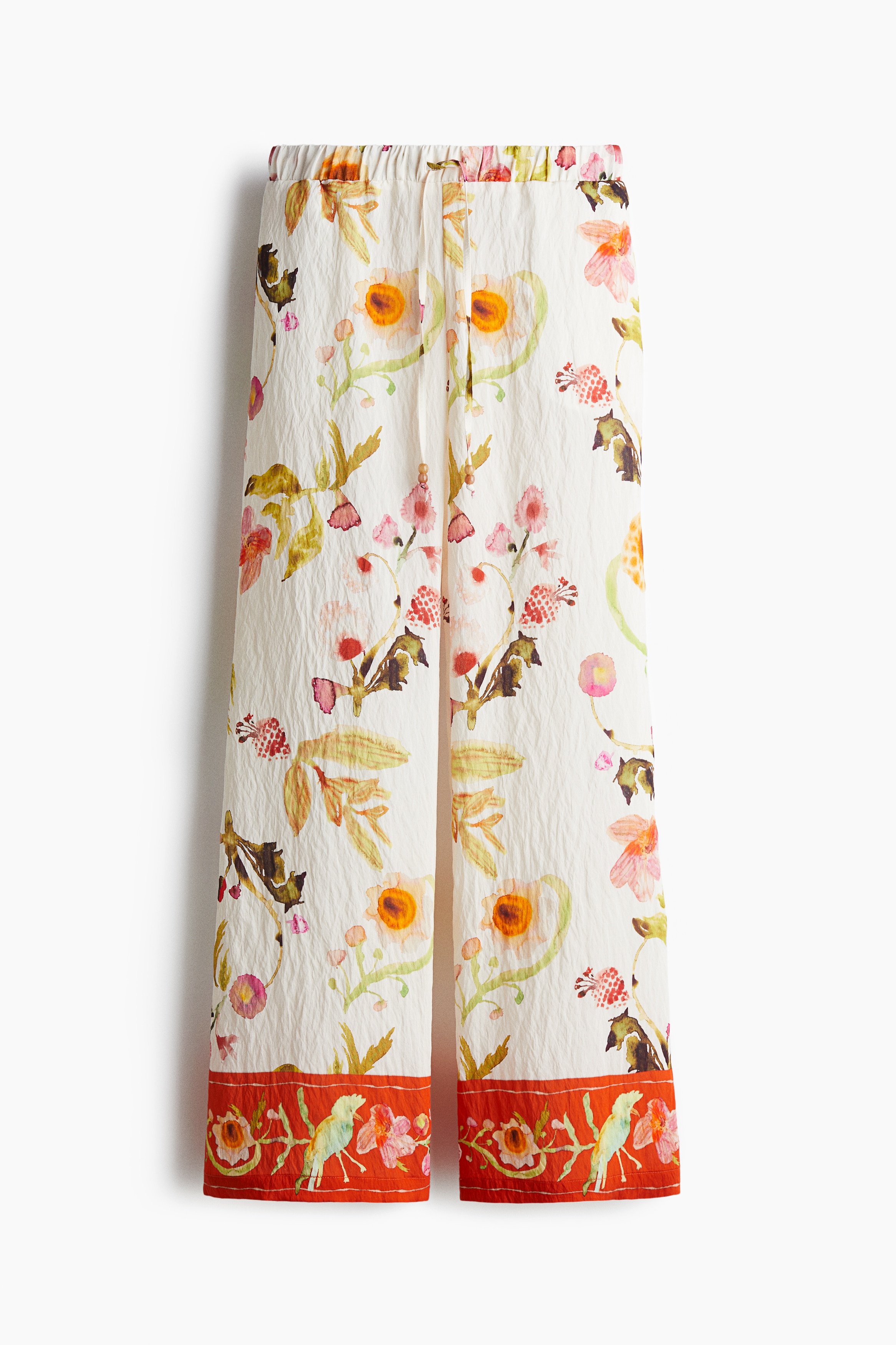 Trousers in a crinkled weave made from a viscose and nylon blend with a colourful all-over print. Regular waist with covered elastication and a drawstring adorned with plastic beads at the ends, discreet side pockets and wide legs. 이미지