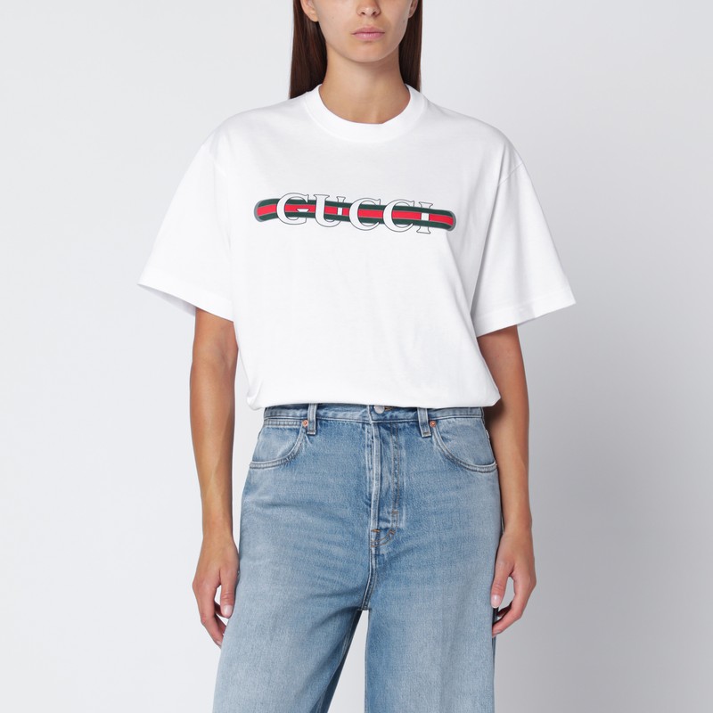 구찌 화이트 코튼 티셔츠로, 반팔 소매, 골지 크루넥, 그리고 가슴 부분에 대비되는 색상의 로고 프린트가 특징입니다. 이미지