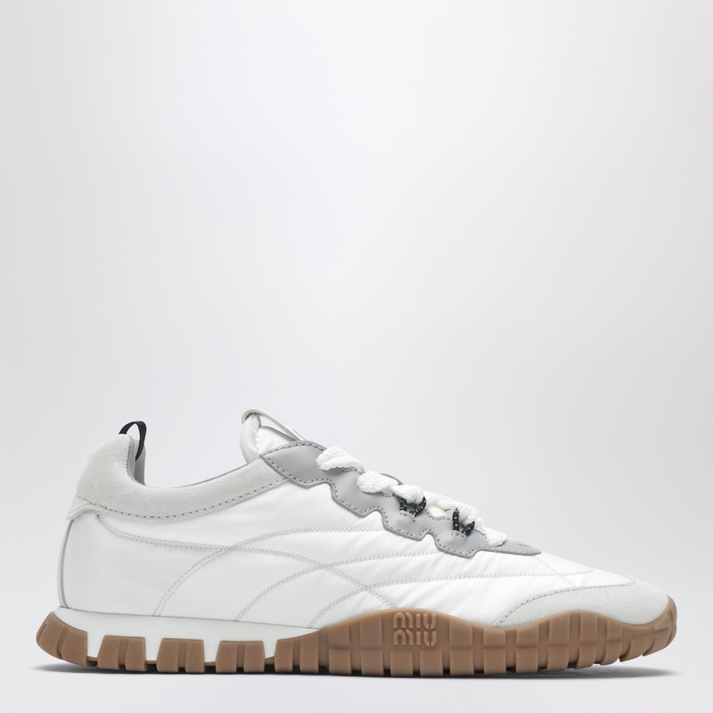 미우미우의 화이트 타이어 스니커즈는 기술적인 패브릭과 스웨이드 소재가 조화롭게 어우러져 편안함과 스타일을 동시에 선사합니다. 패딩 처리된 갑피와 스티칭 디테일이 돋보이며, 패브릭 안감, 레이스업 클로저, 로고가 새겨진 고무 밑창, 탈착 가능한 패브릭 커버 안창, 그리고 설포, 안창, 힐 탭에 스크린 프린트된 로고가 특징입니다. 이미지