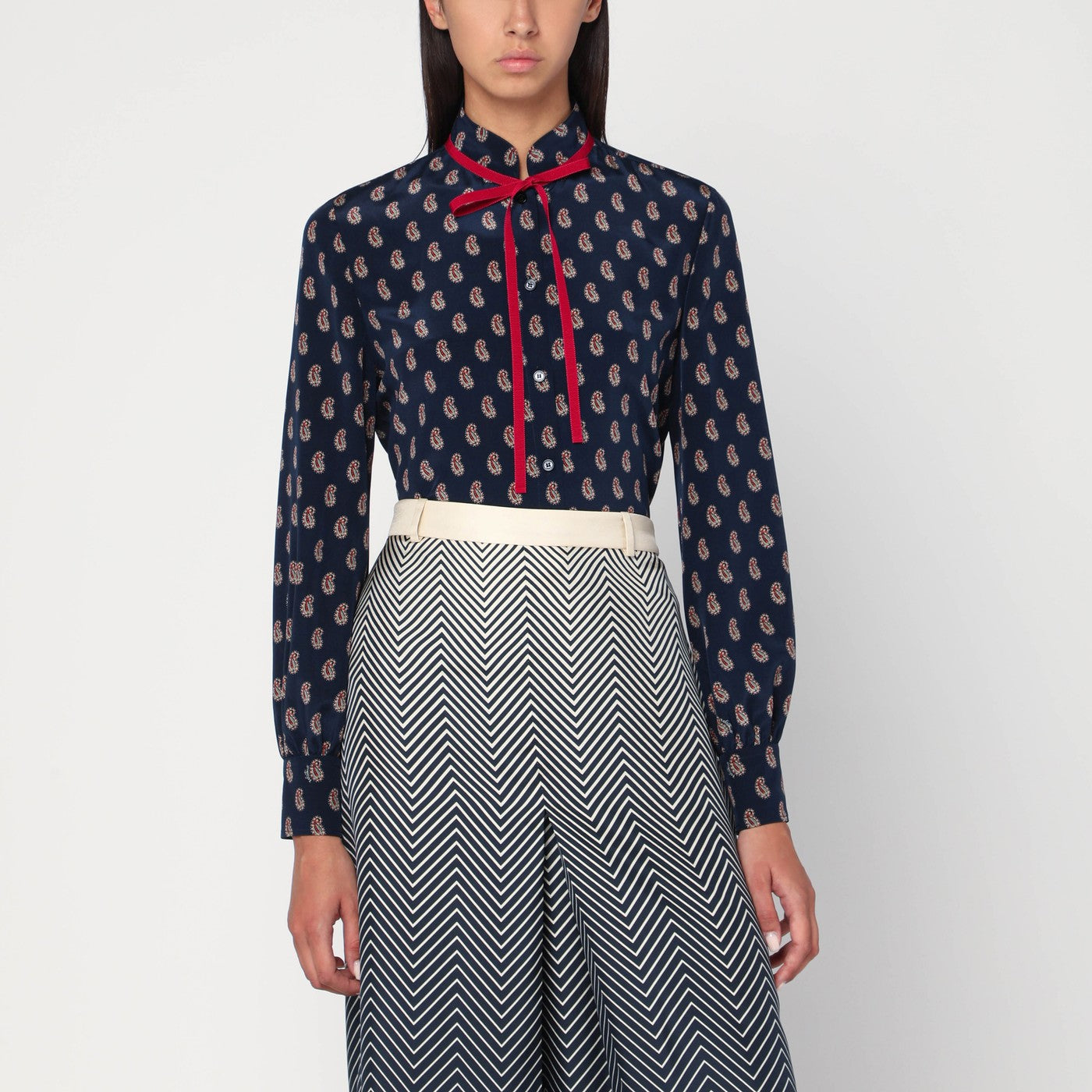 인디고 실크 소재에 전체 페이즐리 프린트가 특징인 발렌티노 셔츠로, 앞면 버튼 잠금과 버튼 커프스 긴 소매, 그리고 목 부분의 레드 타이 리본이 돋보입니다. 이미지