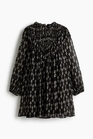 비침성 있는 소재의 A라인 미니 드레스. 프릴 칼라. 뒷면에 키홀 트임과 버튼이 있음. 플리츠가 잡힌 V자 모양의 앞면 요크. 요크 부분의 와이드한 프릴 장식이 어깨를 지나 뒷면으로 이어지는 디자인. 벌룬 스타일의 긴소매. 신축성 소맷단. 어깨 스트랩 길이를 조절할 수 있는 이너 원피스 부착. 이미지