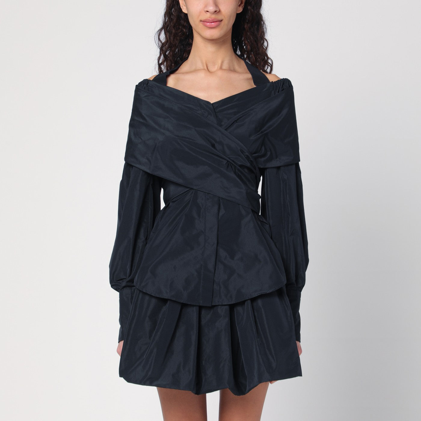 재활용된 블랙-블루 파유 소재로 제작된 파투 블라우스는 앞면의 탈착 가능한 크로스 부분과 뒷면의 넓은 네크라인이 특징이며, 고무줄 밴딩 처리된 어깨와 목을 감싸는 디자인, 숨겨진 단추 여밈, 그리고 단추 커프스가 있는 긴 소매로 구성되어 있습니다. 이미지