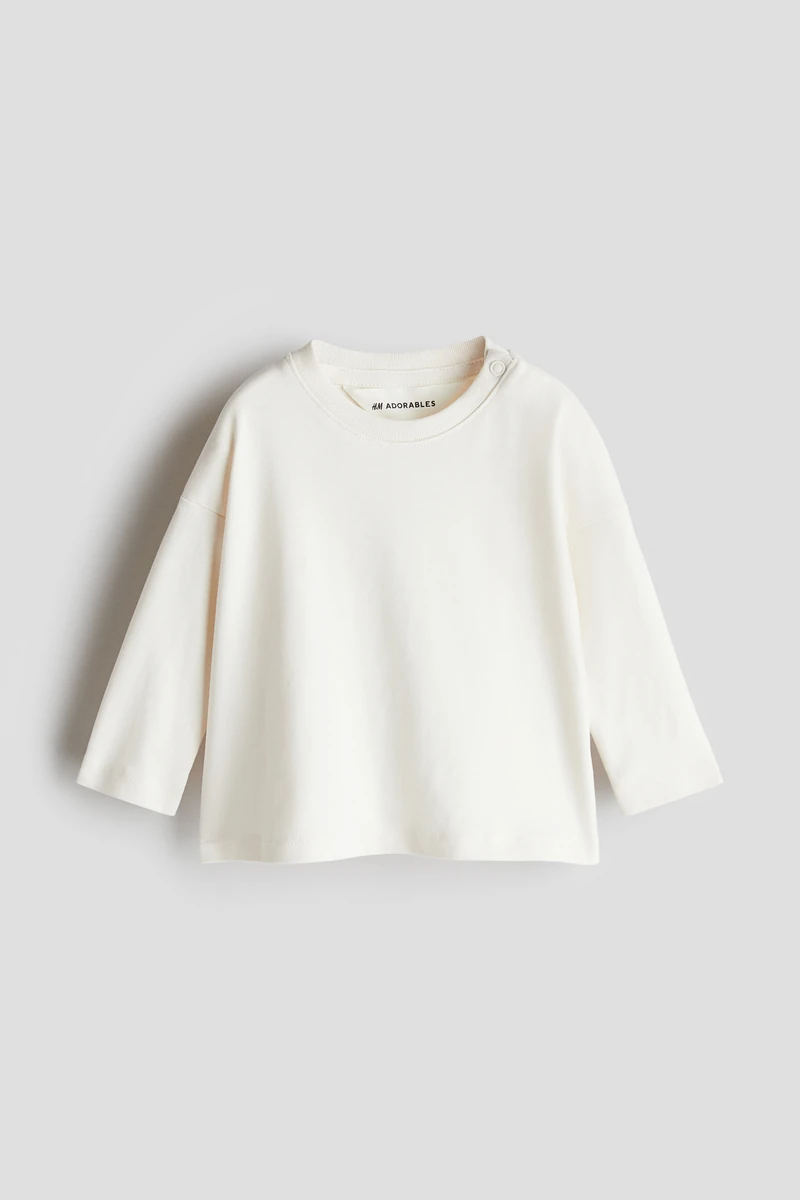 H & M Adorables. 고급 피마 코튼을 사용하여 매우 부드러운 저지 소재의 루즈핏 티셔츠. 리브드 마감된 라운드넥 한쪽 옆면에 스냅버튼이 있음. 드롭 숄더. 긴소매. 높은 GSM으로 도톰하고 견고하면서도 편안한 코튼 저지 소재를 사용합니다. H & M Adorables 컬렉션은 시대를 초월한 매력을 지닌 매우 편안하고 고급스러운 제품들로 엄선된 컬렉션입니다. 이미지1