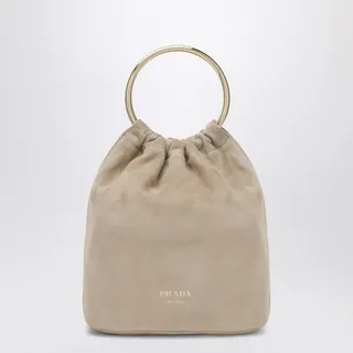 프라다의 사막색 스웨이드 미니 버킷백은 원형 메탈 핸들, 탈착 가능한 숄더 스트랩, 골드 톤 하드웨어, 그리고 앞면에 양각 로고 레터링이 특징입니다. 이미지