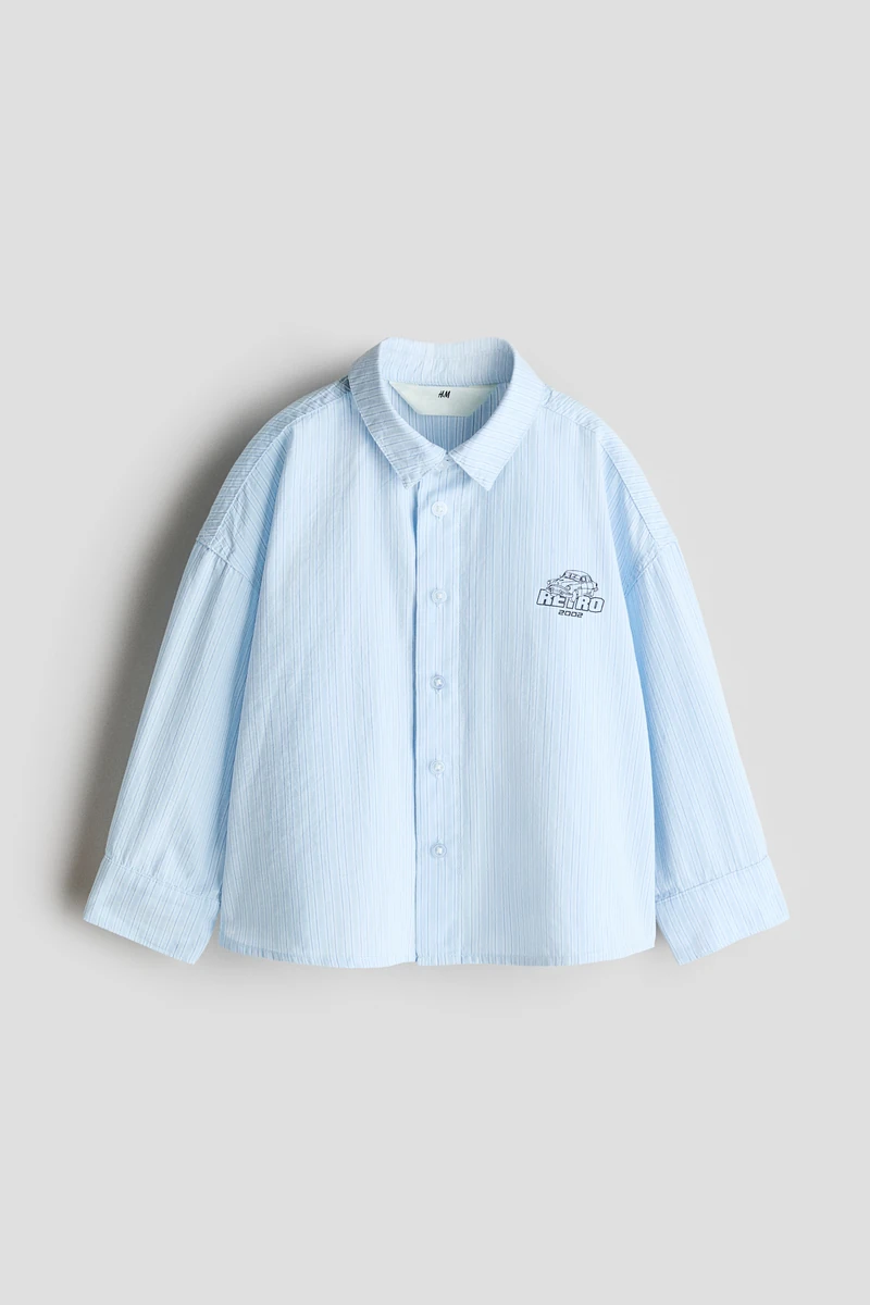Loose-fit shirt in crisp cotton poplin with a small print motif on the front. Collar, buttons down the front and a yoke with a box pleat at the back. Gently dropped shoulders and long sleeves with buttoned cuffs. Gently rounded hem. 이미지1