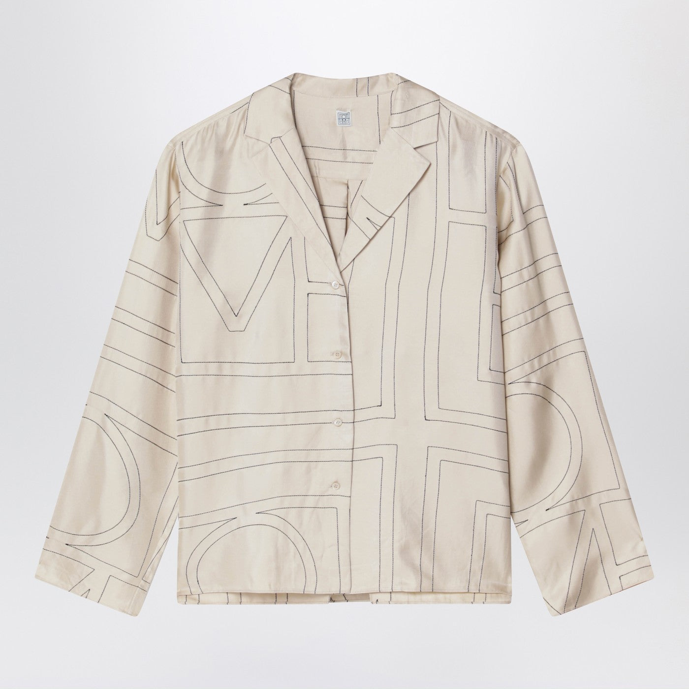 토템의 오버사이즈 아이보리 실크 셔츠는 전체적으로 대비되는 모노그램 패턴, 긴 소매, 전면 버튼 잠금, 오픈 칼라, 그리고 스트레이트 헴 라인을 특징으로 합니다. 이미지