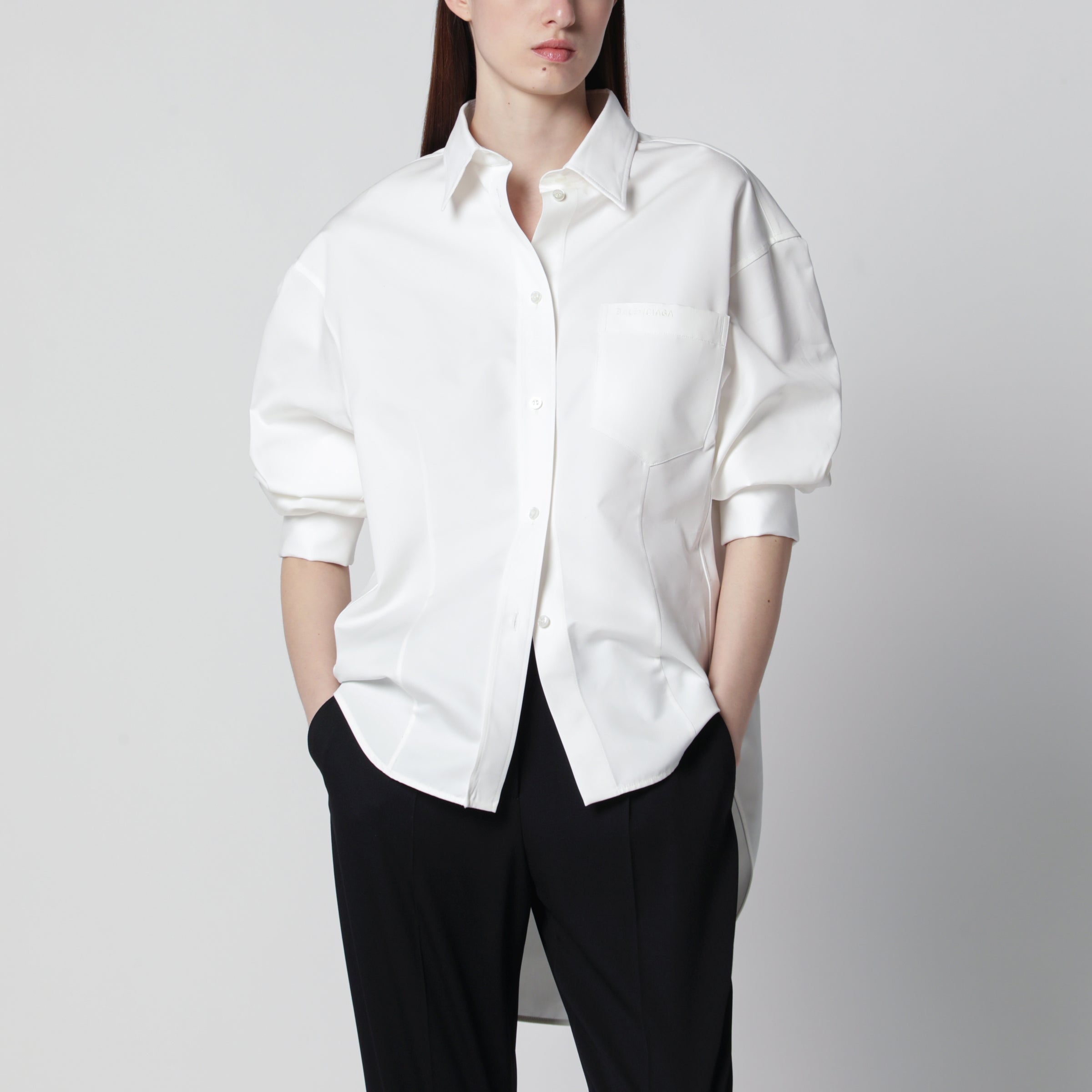 발렌시아가의 여성 클래식 실크 포플린 및 코튼 오간자 셔츠. 화이트 색상. 길어진 뒷면이 특징인 코쿤 스타일 핏. 포인트 칼라. 부드러운 어깨 라인. 5개의 버튼으로 여미는 앞면 버튼 여밈. 발렌시아가 로고가 자수된 가슴 포켓. 긴 소매. 프렌치 커프스. 둥근 밑단. 발렌시아가 로고가 새겨진 버튼. 이미지