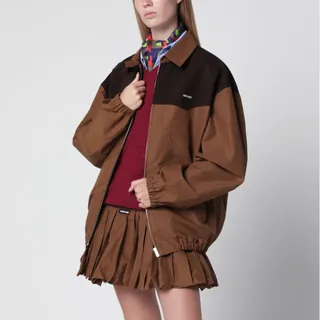코튼 소재의 미우미우 블루종. 카라멜 색상. 질감과 색상 대비를 위한 대조적인 원단 요크 디테일이 있는 비시 체크 패턴. 남성적인 컷과 빈티지에서 영감을 받은 오버사이즈 핏. 안감 없는 의류. 셔츠 칼라. 지퍼 클로저. 엘라스틱 커프스가 있는 긴 소매. 웰트 포켓. 로고 패치. 이미지