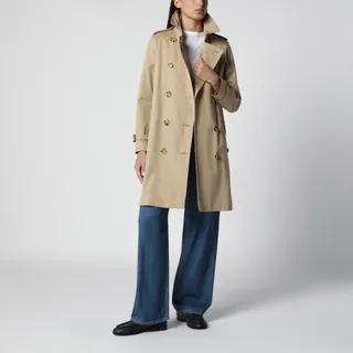 버버리의 코튼 개버딘 소재 트렌치코트입니다. 허니 컬러로, 더블 브레스티드 버튼 클로저와 훅 잠금 칼라, 스로트 래치 디테일이 돋보입니다. B자형 버클 벨트와 버튼 클로저 사이드 포켓, 조절 가능한 커프 스트랩, 백 벤트, 그리고 아이코닉한 체크 프린트 안감이 특징입니다. 이미지