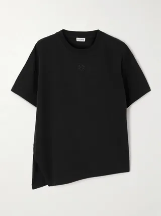 로에베의 티셔츠는 코튼 혼방 저지 소재로 제작되었으며, 크루 넥라인 아래에 상징적인 '아나그램' 로고가 자수 처리되어 있습니다. 박시한 실루엣과 비대칭으로 갈라진 헴라인이 특징입니다. 이미지
