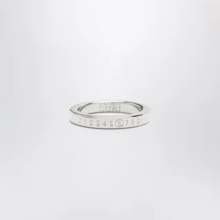 MM6 메종 마르지엘라의 브라스 소재 반지입니다. 샤이니 팔라듐 컬러로 마감되었으며, 3mm 밴드 두께에 전면의 돌출된 숫자 시그니처와 밴드 내부의 숫자 각인 디테일, 브랜드 로고가 특징입니다. 이미지